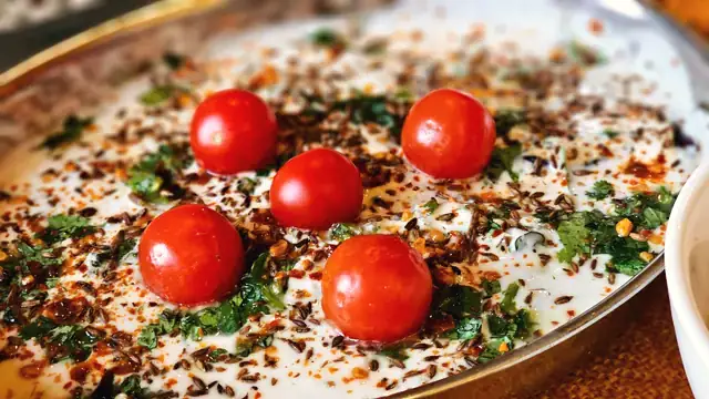 Creamy curd topped with cherry tomatoes, herbs and chilli flakes