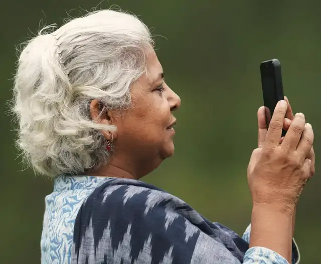 An older woman holding up a phone