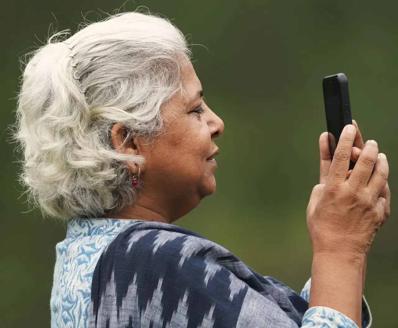 An older woman holding up a phone