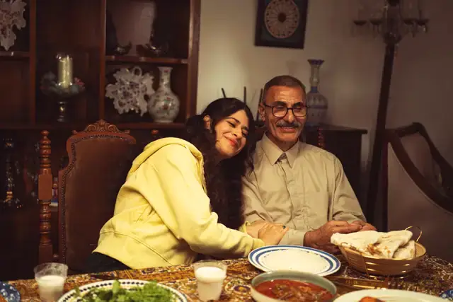 An older man and a young woman smiling together at a family dining table