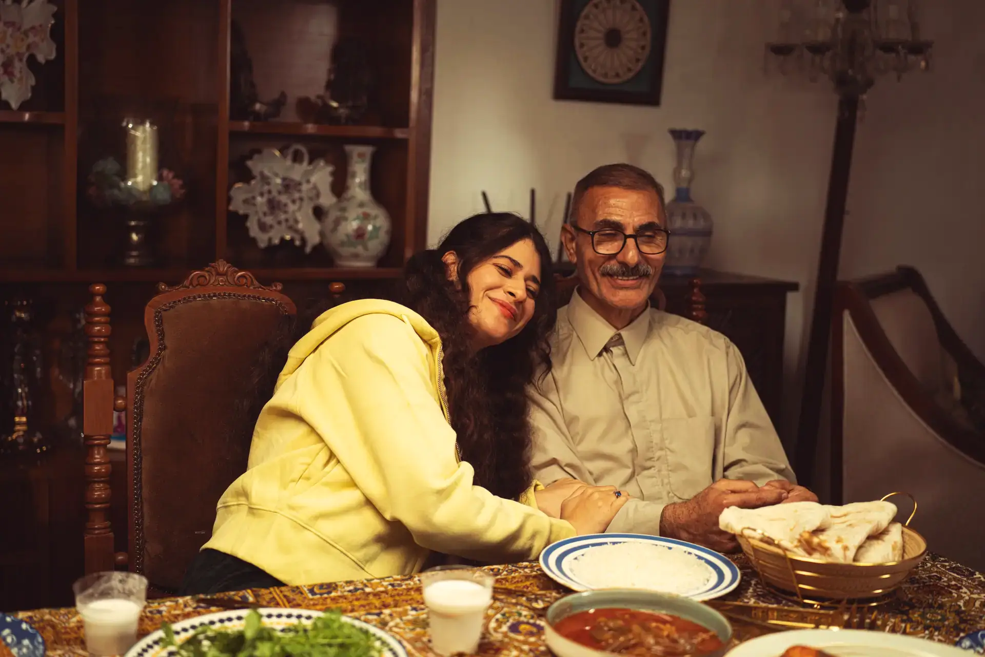 An older man and a young woman smiling together at a family dining table