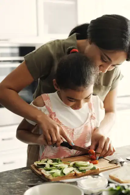 A mother and daughter chopping vegetables together in a kitchen