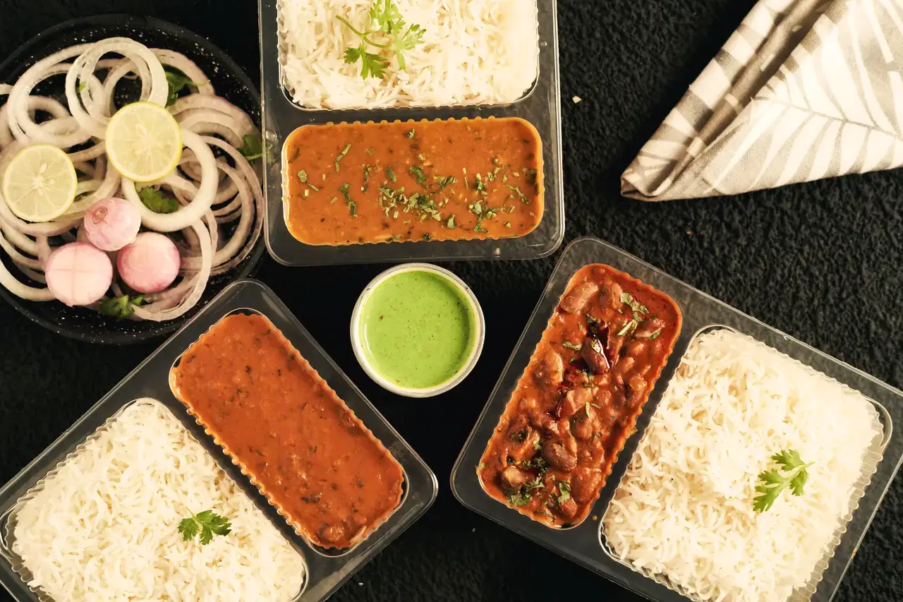 Dal, rajma and steamed rice in lunchbox trays, ready for delivery